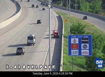 Emergency vehicle on the shoulder of the highway near an exit.
