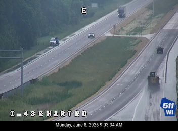 Construction vehicle on the right shoulder of the highway, possibly responding to an incident.