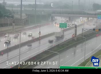 Emergency responder vehicle and personnel on the right shoulder during heavy rain.