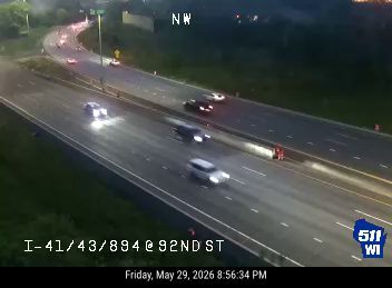 Emergency responder vehicle with flashing lights on the right shoulder of the highway.
