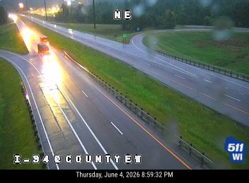 Emergency vehicle with flashing lights on wet highway, possibly responding to an incident.