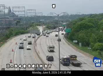 Emergency responders and vehicles on the highway shoulder with traffic cones.