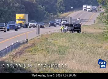 Emergency responders and vehicles are present on the shoulder of the highway.