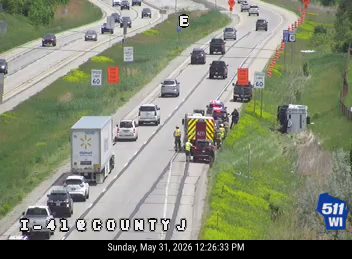 Emergency responders and vehicles are on the side of the highway attending to an incident.