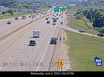 Ambulance and two people on the shoulder of the highway.