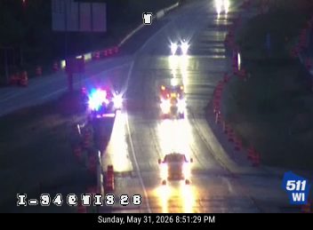 Emergency responders with flashing lights on the roadway, traffic is stopped.