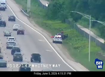 Police and other vehicles are stopped on the shoulder of the highway.