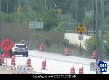 Emergency responders and traffic cones are present on the roadway.