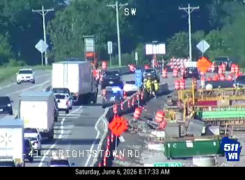 Road construction with cones and barriers, traffic is moving slowly.