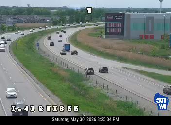 Police vehicles are stopped on the shoulder of the highway.