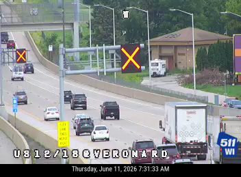 Emergency vehicle with flashing lights on the right shoulder, traffic slowing.